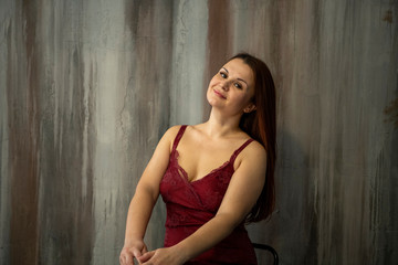beautiful girl in a burgundy dress posing on a dark background
