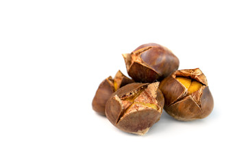 Multiple roasted chestnuts. (Castanea). Sweet edible chestnuts are scored with an X. Seasonal fall and winter tree nut. Holiday dinner and Thanksgiving side dish. Isolated on white. Copy space.