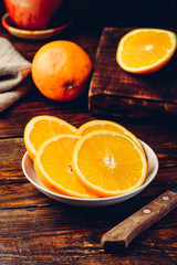 Slices of orange on white plate in rustic setting