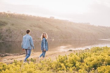 Fototapeta na wymiar couple in love in blue jeans and white shirts in nature, where the field and rocks
