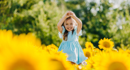 Little cheerful girl in a field of yellow sunflowers. Child and sunflower, summer, nature and fun....