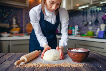 Faceless shot of woman in white shirt and apron flour dough while cooking.