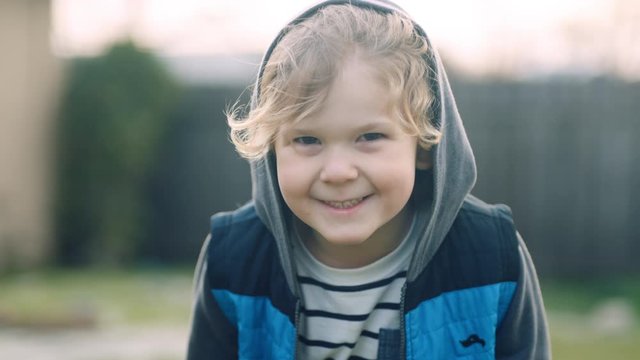 Portrait of 4 year old boy smiling sweetly while looking at camera slow motion