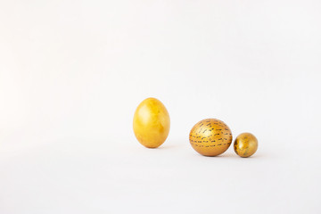 Golden Easter holiday eggs on a white background. Two beautiful painted eggs on a festive table