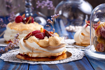 Many desserts Pavlova with raspberries and figs on old blue wooden table. Meringues on a rustic background