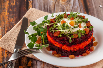 A healthy detox salad with beets, carrots, microgreen and raisins. Vegetarian vegan food on a wooden background.