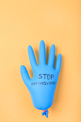 Protective blue rubber glove with STOP CORONAVIRUS text on yellow background.