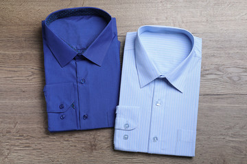 Stylish folded shirts on wooden table, flat lay. Dry-cleaning service