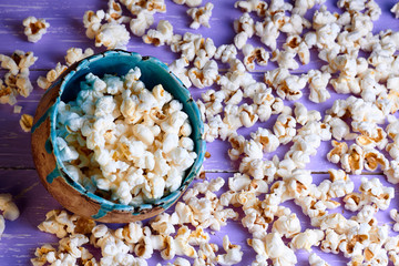 Popcorn in brown handmade clay bowl on purple wooden table