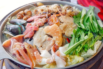 Sliced Pork and seafood on Thai Styled Coal Grill and Shabu Pan.Shrimp Clams in a Hot Pan.Close up.
