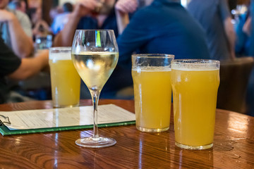 A white wine glass next to beer glasses on a wooden table at a bar in Brisbane, Australia.