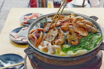 Sliced Pork and seafood on Thai Styled Coal Grill and Shabu Pan.Shrimp Clams in a Hot Pan.Close up.

