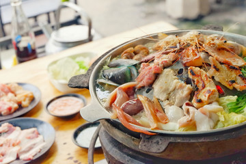 Sliced Pork and seafood on Thai Styled Coal Grill and Shabu Pan.Shrimp Clams in a Hot Pan.Close up.
