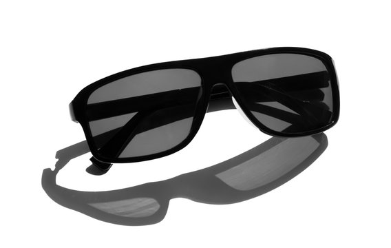 stylish black sunglasses on a white background with a shadow from the sun