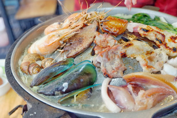 Sliced Pork and seafood on Thai Styled Coal Grill and Shabu Pan.Shrimp Clams in a Hot Pan.Close up.
