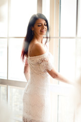 happy young woman in white dress in front off the window