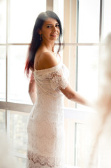 happy young woman in white dress in front off the window