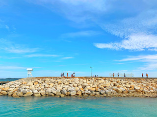 Fototapeta na wymiar Rocks extending into the sea.View of the sea and a wooden bridge extending into the sea, with Thai characters written as 