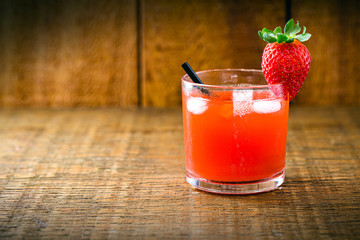 Brazilian caipirinha, cachaça drink with fruits, on wooden background. Strawberry flavor