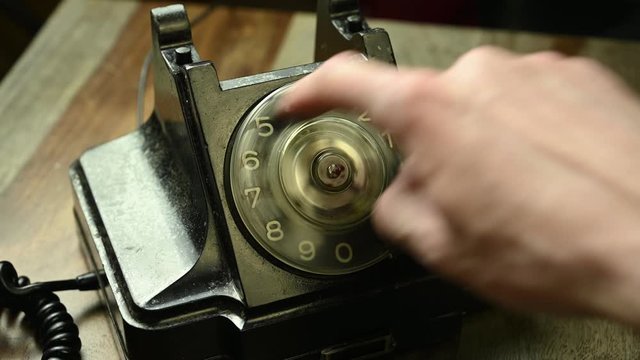 man picks up phone on old phone and turns number plate of phone