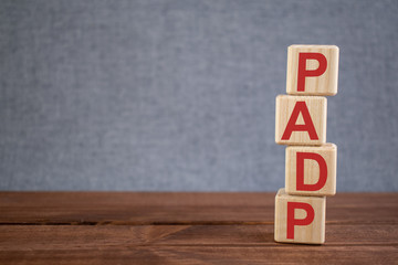 Abbreviation PADP (pulmonary artery diastolic pressure) text acronym on wooden cubes on dark wooden backround. Medicine concept.