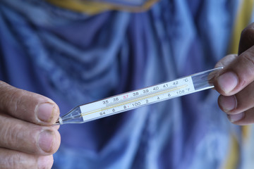 senior women hand holding thermometer, close up 