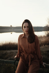 Portrait of young woman by lake at sunset