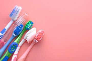 Multi color tooth brushes pink background, top view 