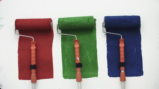 Farbrolle malt rot gr&uuml;ne blaue Streifen auf wei&szlig;er Wand