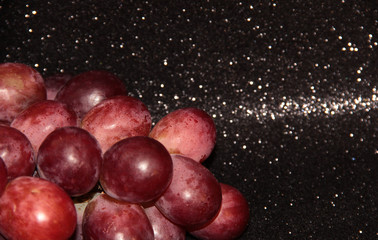 Large pink grapes on a black shiny background.