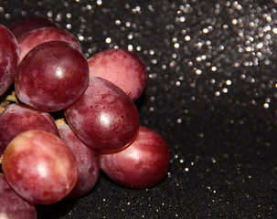 Large pink grapes on a black shiny background.