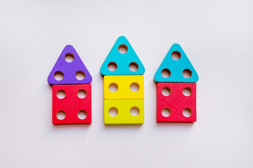 Children's toy made of wood on a white background close-up, the child plays with a constructor, a sorter. Children's room with toys. Constructor in the hands of a child. Wooden houses on the backgroun