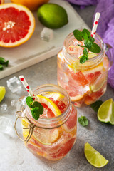 Ice refreshing drink. Mason jar mug filled with Fresh mojito cocktail with grapefruit, lime and mint on a background of gray stone.