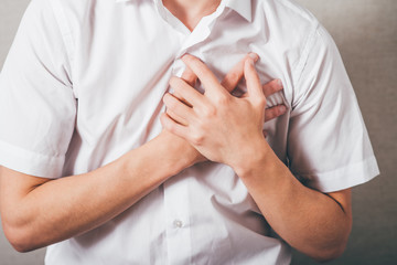 The man put his hands on his chest, the heart. On a gray background.