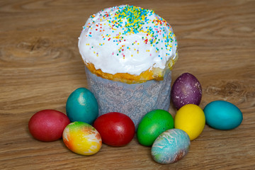
Easter cake with colored sprinkles and multi-colored bright colored eggs on a wooden background