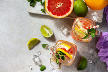 Summer ice refreshing drink. Fresh mojito cocktail with grapefruit, lime and mint in a glass on a gray stone background. Top view flat lay background.