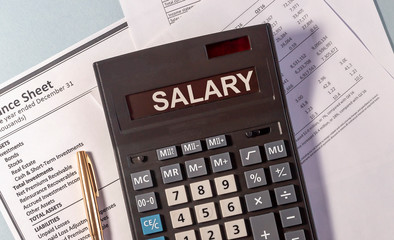 Calculator with the word "Salary" and pen on documents