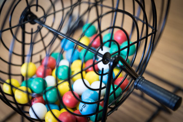 A close up of a bingo cage filled with multi-colored balls. Each ball has a letter and number on it...