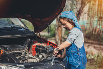 Little child trying to fix broken real car. Dreaming to be auto technician