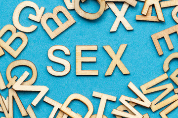 Wort SEX aus Holzbuchstaben auf blauem Hintergrund