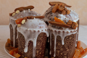 Four stylish delicious Easter cakes together at the plate decorated by dried bananas, orange apricots, almonds and small elegant sugar silver pearl beads. Traditional Orthodox Easter bread - kulich