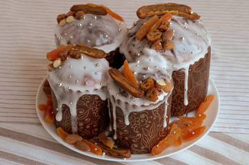 Traditional Orthodox Easter bread - kulich. Four stylish delicious Easter cakes together at the plate decorated by dried bananas, orange apricots, almonds and small elegant sugar silver pearl beads