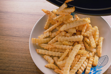French fries on a plate, On the wood table background, Delicious and healthy because cooking in an oil-free frying pan, Selective focus.