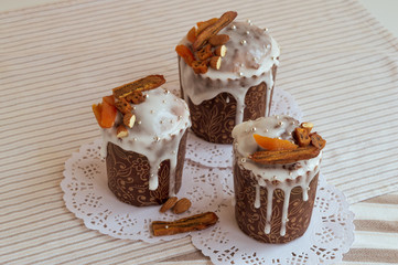 Traditional Orthodox Easter bread - kulich. Three stylish delicious Easter cakes together on the white napkins decorated by dried bananas, orange apricots, almonds and elegant sugar silver pearl beads