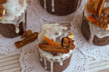 Top view of four stylish delicious cakes together at napkins decorated by dried bananas, orange apricots, almonds and small elegant sugar silver pearl beads. Traditional Orthodox Easter bread kulich