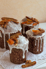 Orthodox Easter delicious homemade cakes on the white napkins decorated by dried bananas, orange apricots, almonds and small elegant sugar silver pearl beads. Vertical photo of four stylish cakes