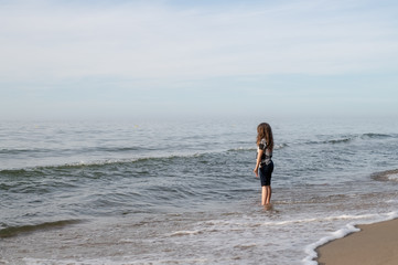 One long-haired girl running along the shore of the silver-colored North sea. Windy weather, Northern landscape, pastel color.