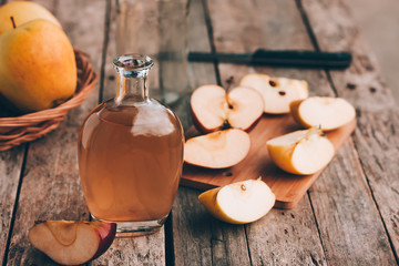Apple organic vinegar in glass pitcher with ripe fresh red and yellow apples on wooden rustic table. Healthy organic food concept. Selective focus
