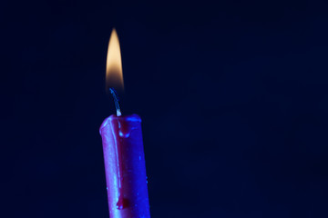 blue burning candle on black background