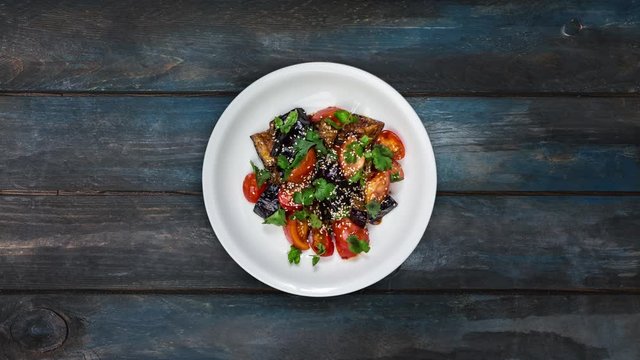 Rotating salad of fried eggplant with tomatoes in Asian dressing.
